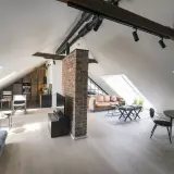 Stilvolle dachgeschosswohnung einrichten: Offener Wohnbereich mit Küche, Ledersofa und Essbereich unter Dachschrägen.