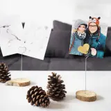 Selbstgemachte Fotohalter aus Holzscheiben und Draht mit Fotos von einem Paar und einem Vogel. Perfekt, um Erinnerungen zu präsentieren.