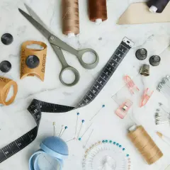 Nähutensilien wie Knöpfe von Stoff und Stil, Schere, Maßband und Garn. Perfekt für kostenlose Schnittmuster-Projekte.