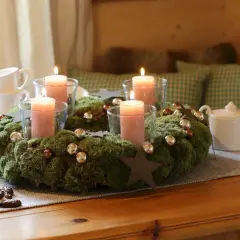 Ein Adventskranz aus Moos mit vier rosa Kerzen, Kugeln und Sternen. Tolle Adventsdeko Ideen für ein gemütliches Zuhause.