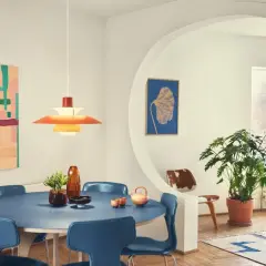 Ein Esszimmer im **midcentury modern** Stil mit blauem Tisch, blauen Stühlen, einer bunten Wandkunst und einer markanten Hängeleuchte.