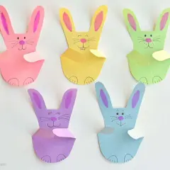 Fünf bunte Papierhasen, jeder ein einfacher hase, sitzen nebeneinander.
