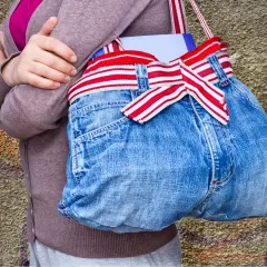 Kreative Tasche aus Jeans-Upcycling, mit rot-weiß gestreiftem Band und einer Schleife. Perfekt für Bücher und mehr.