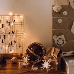 DIY Adventskalender basteln für Erwachsene: Ein Drahtgitter mit nummerierten Zetteln, Lichterkette und Bastelmaterialien.