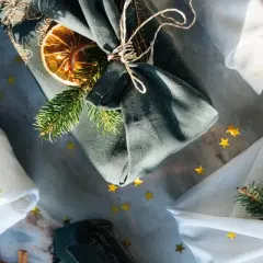 Geschenke liebevoll verpackt mit Stoff. Eine furoshiki anleitung für nachhaltige Geschenke, verziert mit Tannenzweigen und Orangenscheiben.