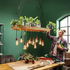 Frau dekoriert eine selbstgemachte Lampe mit Pflanzen. Ein DIY-Projekt für ein grünes Zuhause.