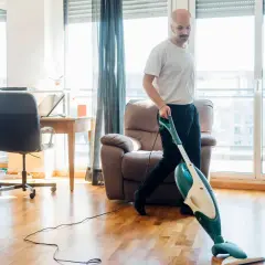 Mann saugt Parkettboden. Ein guter Tipp für omas tipp parkett reinigen: Regelmäßig saugen hält den Boden schön.