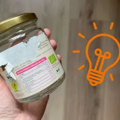 Ein Glas mit einem teilweise abgezogenen Aufkleber. Ein Tipp, wie man den Aufkleber von Glas entfernen kann, wird hier gezeigt.