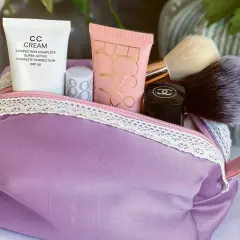 Lila Kosmetiktasche mit Make-up-Produkten und Pinseln. Hier findest du ein schnittmuster kosmetiktasche kostenlos zum Selbernähen.