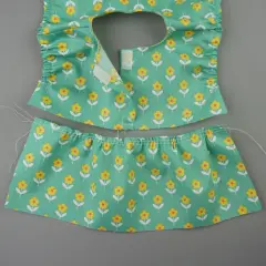 Zwei Teile eines **Puppenkleid Schnittmusters** mit Blumenmuster: Oberteil mit Rüschen und Klettverschluss, Rockteil mit Gummizug.