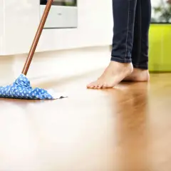 Barfuß wird der Holzboden mit einem blauen Wischmopp gereinigt. Was ist Schmierseife? Sie ist ein natürliches Reinigungsmittel, das sich gut für Böden eignet.