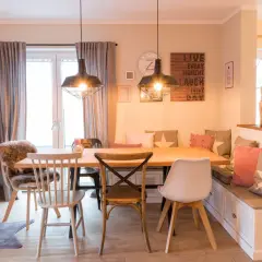 Gemütliches Esszimmer gestalten mit Holztisch, Bank und Stühlen. Dekorative Kissen und Wandbilder schaffen eine einladende Atmosphäre.