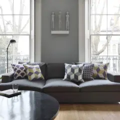 Graues Sofa mit Kissen in Lila, Gelb und Grau. Die Farben passen gut zu Grau und schaffen eine gemütliche Atmosphäre.