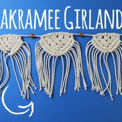 Makramee Girlande selbst machen: Eine bezaubernde, handgeknüpfte Deko mit Fransen und Holzperlen auf blauem Hintergrund.