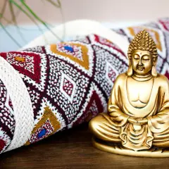 Goldene Buddha-Figur neben einer gerollten Yogamatte mit ethnischem Muster. Vielleicht das Schnittmuster für eine Yogatasche?