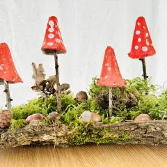 Zauberhafte herbstdeko diy: Fliegenpilze aus Eierkartons auf Moos und Baumrinde, dekoriert mit Zapfen und Kastanien.