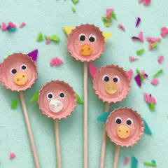 Fünf süße Schweinchen-Gesichter, gebastelt mit Kronkorken, Augen und Knöpfen. Eine tolle Idee zum Basteln mit Kronkorken!