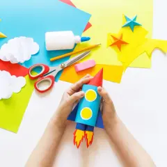 Kinder basteln einen Raketen-Weltraumflug. Alles für bastelkleber selber machen liegt bereit: Papier, Schere, Kleber, Stift.