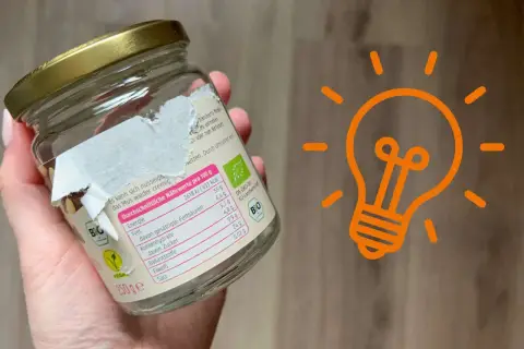 Ein Glas mit einem teilweise abgezogenen Aufkleber. Ein Tipp, wie man den Aufkleber von Glas entfernen kann, wird hier gezeigt.