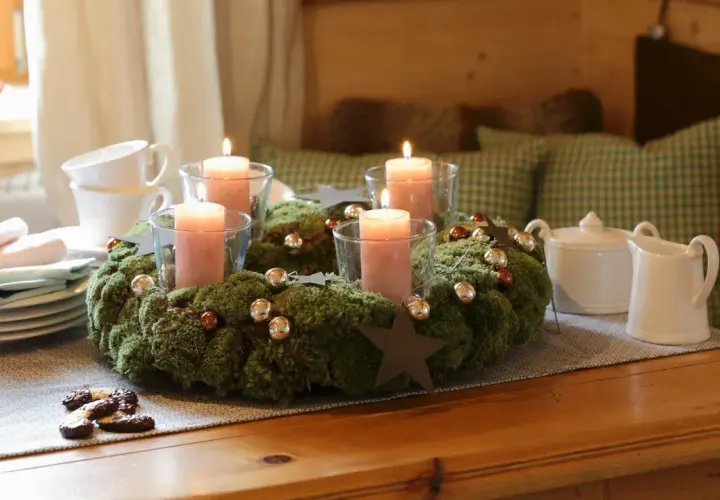 Ein Adventskranz aus Moos mit vier rosa Kerzen, Kugeln und Sternen. Tolle Adventsdeko Ideen für ein gemütliches Zuhause.