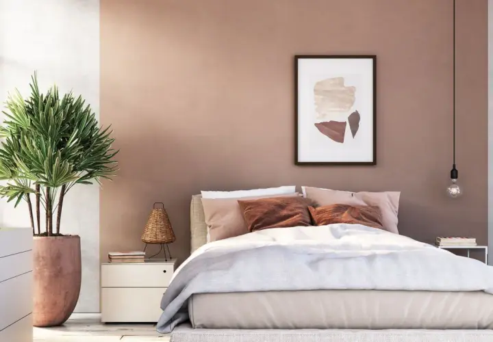 Gemütliches Schlafzimmer mit warmen Wandgestaltung Farben in Rosé- und Erdtönen. Ein Bett mit beiger Bettwäsche und braunen Kissen lädt zum Entspannen ein.