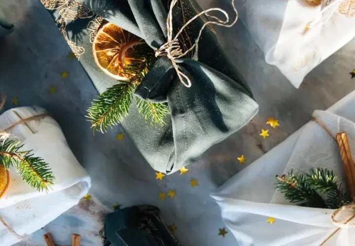 Geschenke liebevoll verpackt mit Stoff. Eine furoshiki anleitung für nachhaltige Geschenke, verziert mit Tannenzweigen und Orangenscheiben.