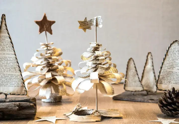 Deko basteln mit alten Buchseiten: Kleine, handgefertigte Weihnachtsbäume aus Papier, verziert mit Sternen.