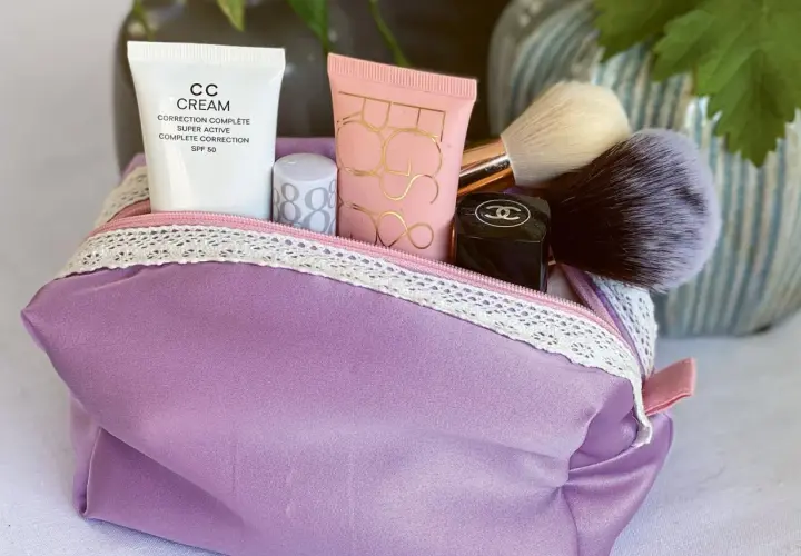 Lila Kosmetiktasche mit Make-up-Produkten und Pinseln. Hier findest du ein schnittmuster kosmetiktasche kostenlos zum Selbernähen.