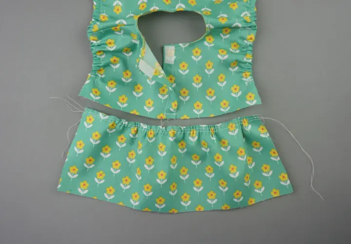 Zwei Teile eines **Puppenkleid Schnittmusters** mit Blumenmuster: Oberteil mit Rüschen und Klettverschluss, Rockteil mit Gummizug.