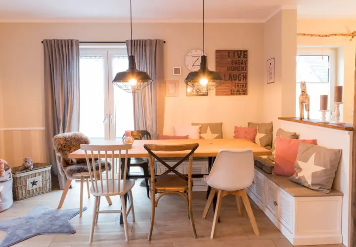 Gemütliches Esszimmer gestalten mit Holztisch, Bank und Stühlen. Dekorative Kissen und Wandbilder schaffen eine einladende Atmosphäre.