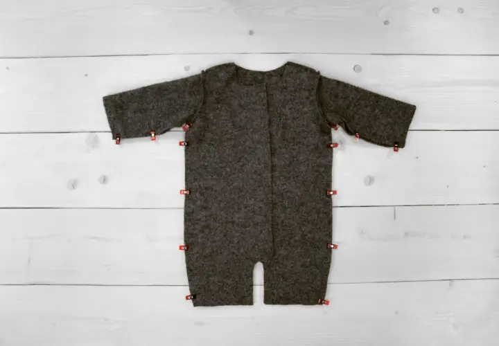 Graues Overall-Schnittmuster, bereit zum Nähen, mit roten Klammern fixiert. Ein tolles, **overall schnittmuster kostenlos** Projekt für DIY-Fans.