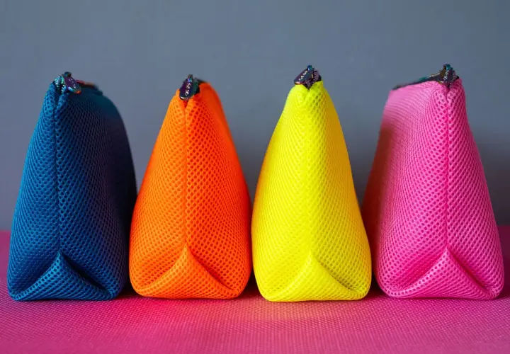 Vier bunte Netzbeutel in Blau, Orange, Gelb und Pink. Ein einfaches schnittmuster tasche, perfekt für Kosmetik oder Stifte.