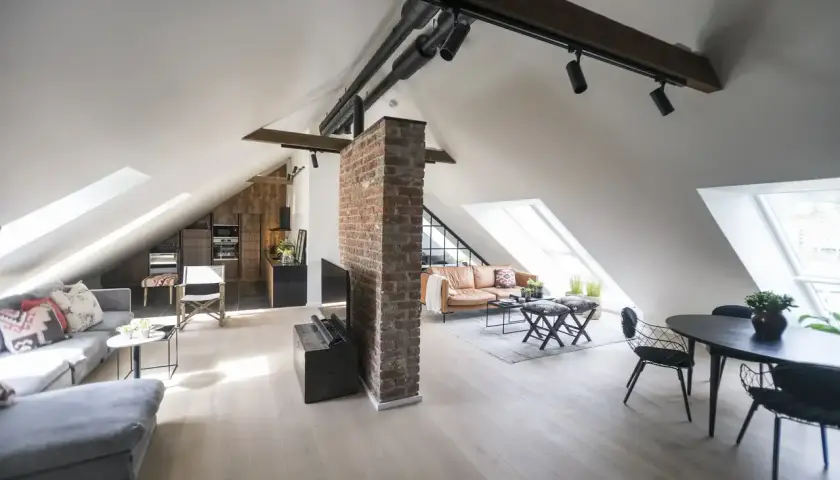 Stilvolle dachgeschosswohnung einrichten: Offener Wohnbereich mit Küche, Ledersofa und Essbereich unter Dachschrägen.