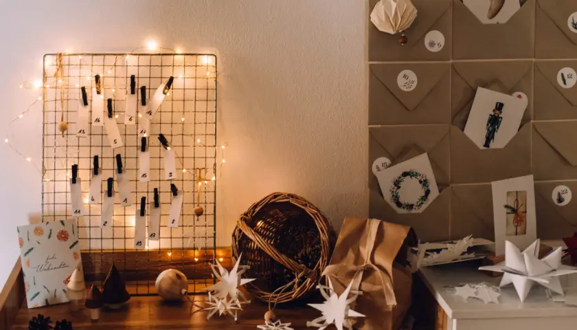 DIY Adventskalender basteln für Erwachsene: Ein Drahtgitter mit nummerierten Zetteln, Lichterkette und Bastelmaterialien.