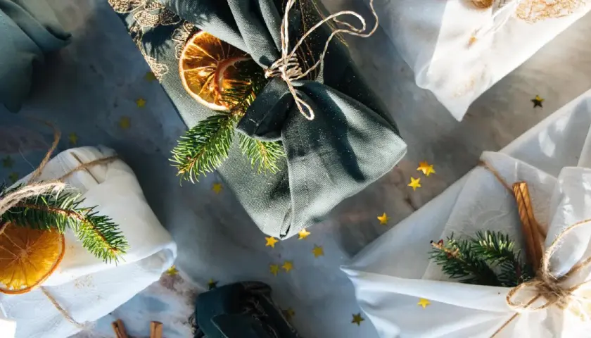 Geschenke liebevoll verpackt mit Stoff. Eine furoshiki anleitung für nachhaltige Geschenke, verziert mit Tannenzweigen und Orangenscheiben.