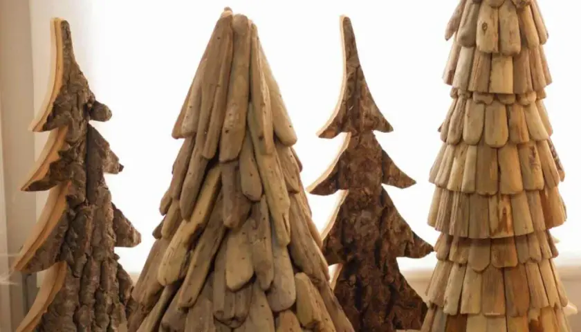 Rustikale Weihnachtsdeko Holz selber machen: Vier handgefertigte Bäume aus Holzstücken und Rinde, die an Tannen erinnern.