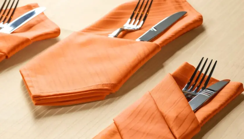 Orange Stoffservietten mit bestercktasche falten papier vorlage. Gedeckter Tisch für ein Festessen.