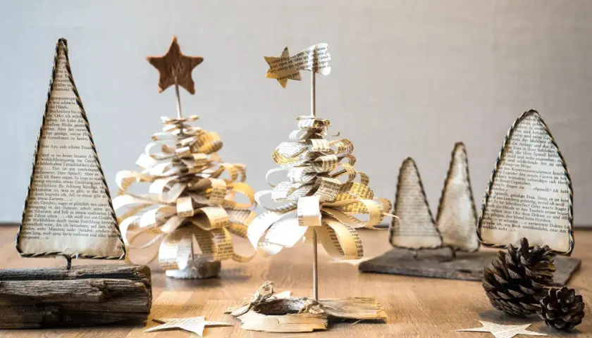 Deko basteln mit alten Buchseiten: Kleine, handgefertigte Weihnachtsbäume aus Papier, verziert mit Sternen.