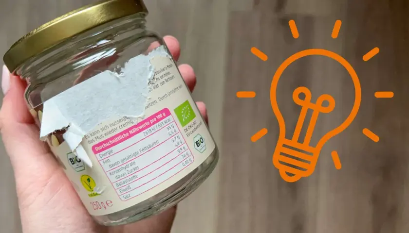 Ein Glas mit einem teilweise abgezogenen Aufkleber. Ein Tipp, wie man den Aufkleber von Glas entfernen kann, wird hier gezeigt.