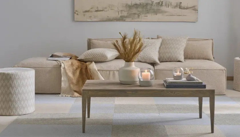 Gemütliches Wohnzimmer im scandi style wohnen: Beige Couch, Holztisch mit Kerzen und Deko, gemustertes Pouf und Teppich.