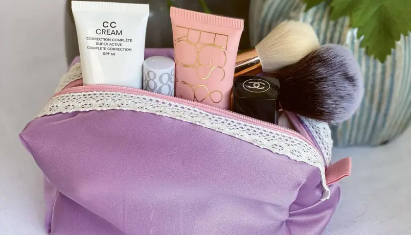 Lila Kosmetiktasche mit Make-up-Produkten und Pinseln. Hier findest du ein schnittmuster kosmetiktasche kostenlos zum Selbernähen.