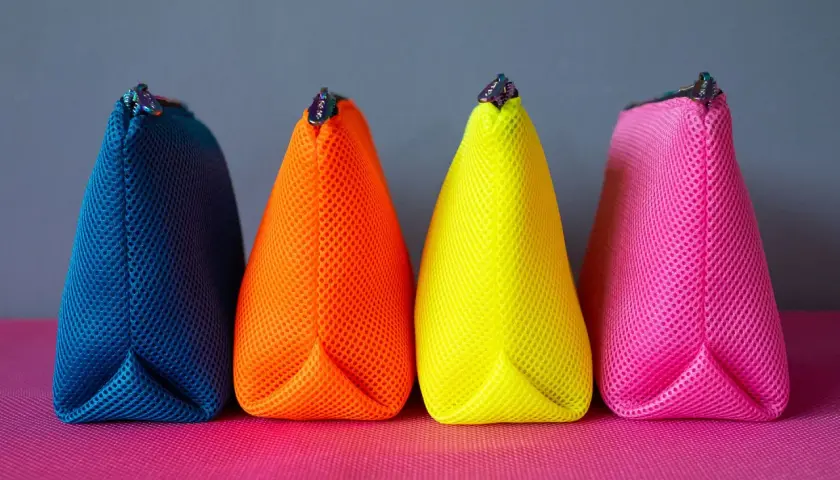 Vier bunte Netzbeutel in Blau, Orange, Gelb und Pink. Ein einfaches schnittmuster tasche, perfekt für Kosmetik oder Stifte.
