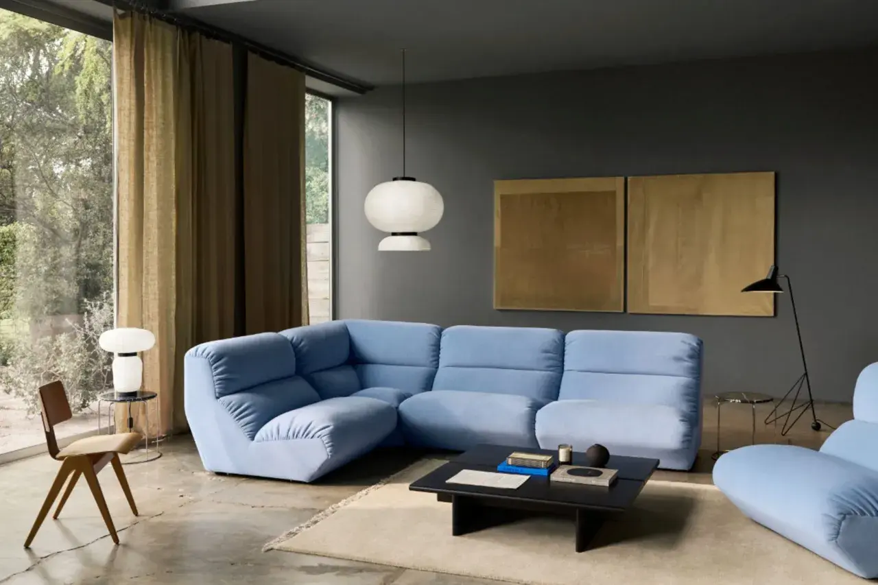 Moderne Wohnzimmer-Ideen: Hellblaues Ecksofa, dunkle Wandfarbe, goldene Kunstwerke und ein minimalistischer Stil.
