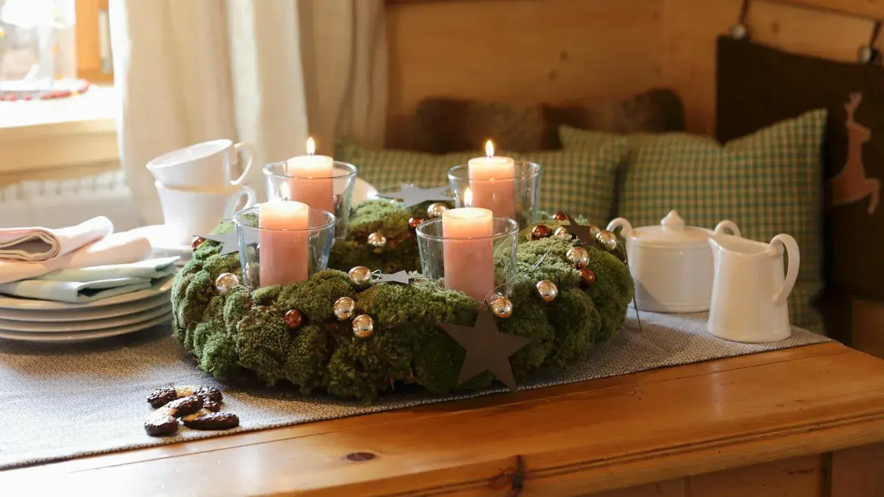 Ein Adventskranz aus Moos mit vier rosa Kerzen, Kugeln und Sternen. Tolle Adventsdeko Ideen für ein gemütliches Zuhause.