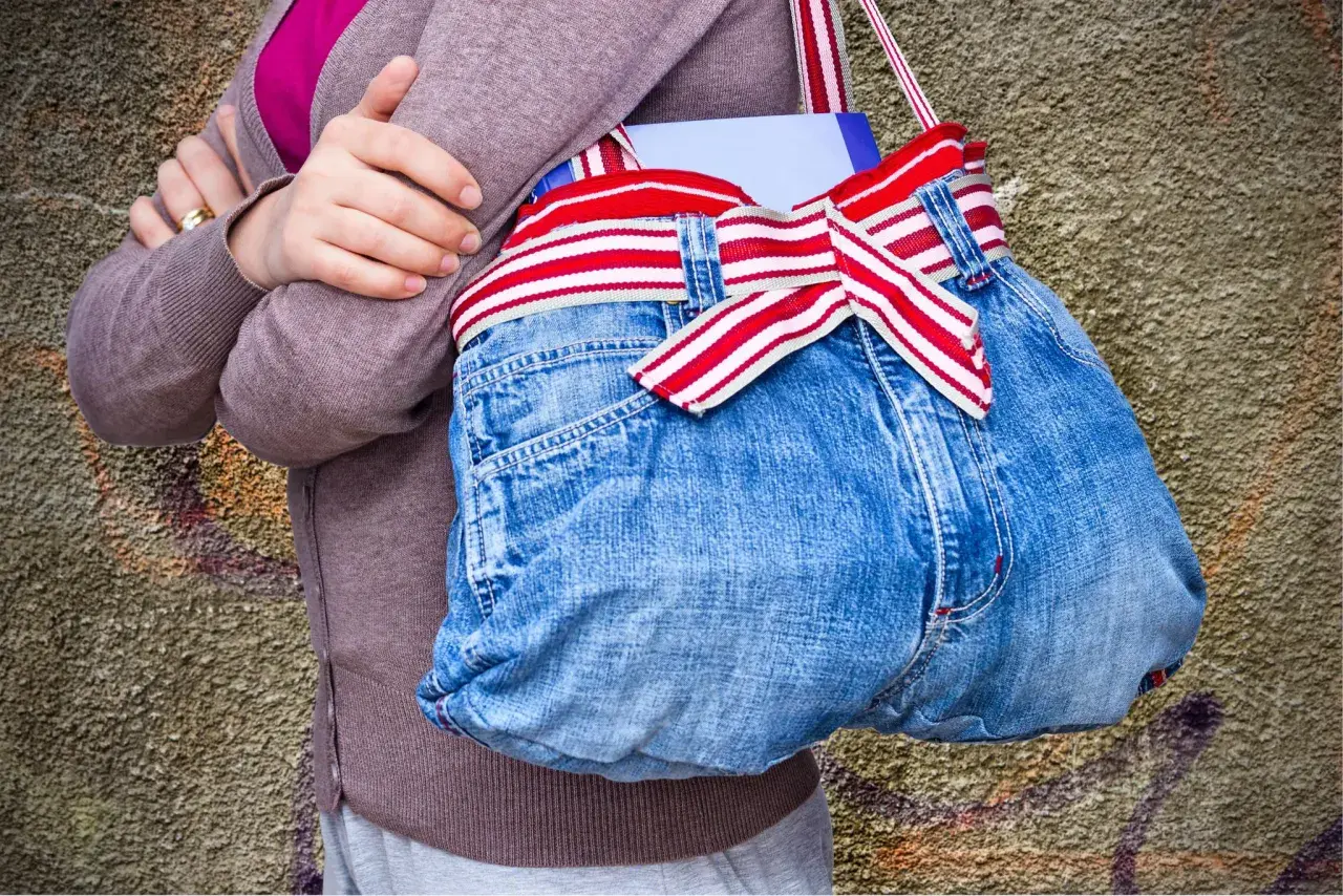 Kreative Tasche aus Jeans-Upcycling, mit rot-weiß gestreiftem Band und einer Schleife. Perfekt für Bücher und mehr.