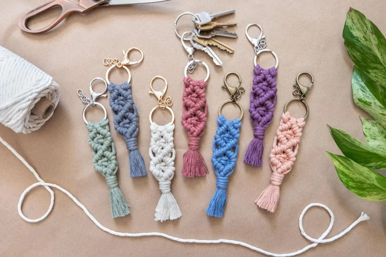 Bunte Makramee-Schlüsselanhänger mit Quasten, tolle Makramee-Ideen für DIY-Projekte. Dazu eine Schere, Garnrolle und Schlüssel.
