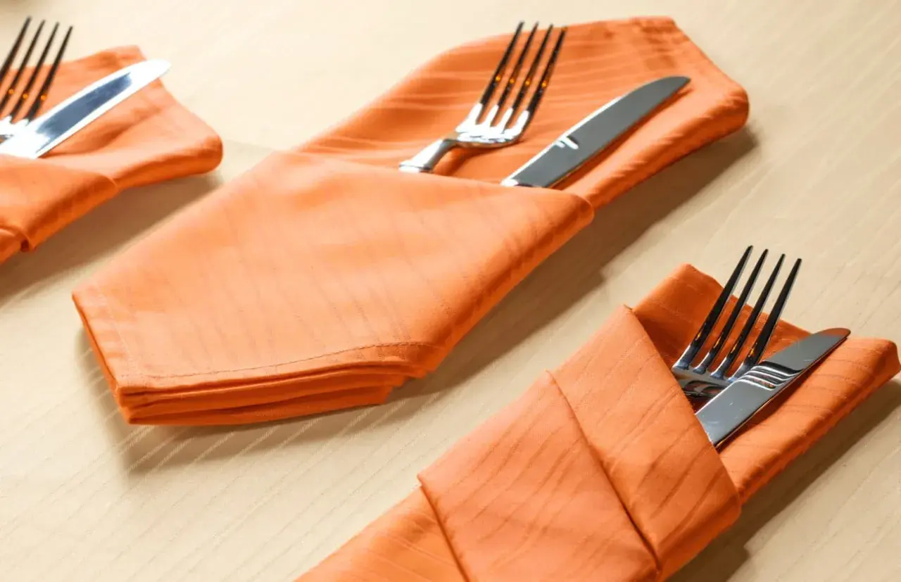 Orange Stoffservietten mit bestercktasche falten papier vorlage. Gedeckter Tisch für ein Festessen.