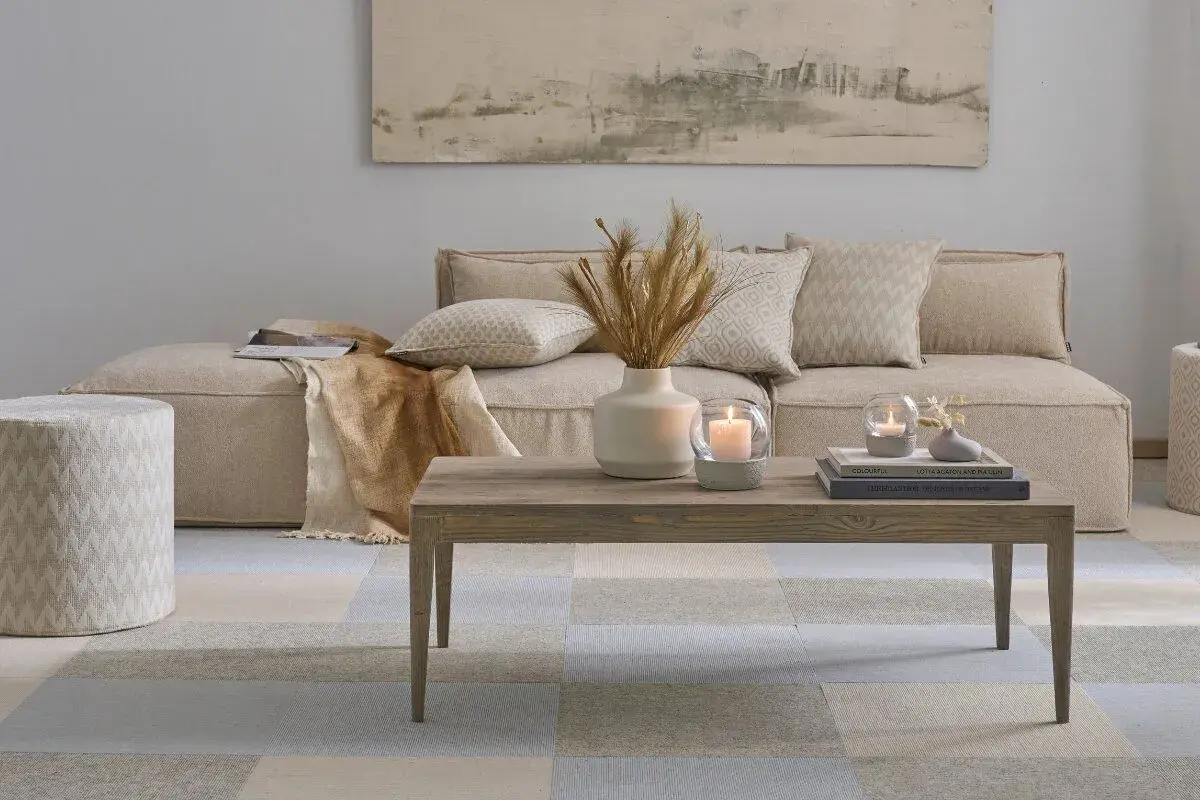 Gemütliches Wohnzimmer im scandi style wohnen: Beige Couch, Holztisch mit Kerzen und Deko, gemustertes Pouf und Teppich.