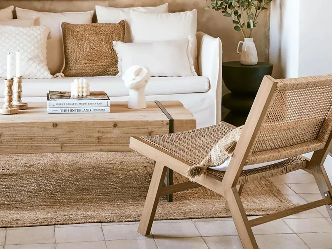 Gemütliches Wohnzimmer im Boho-Stil mit Rattan-Stuhl, Naturmaterialien und erdigen Tönen.