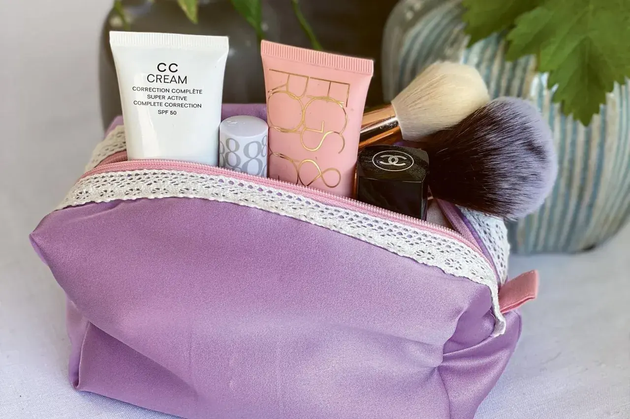 Lila Kosmetiktasche mit Make-up-Produkten und Pinseln. Hier findest du ein schnittmuster kosmetiktasche kostenlos zum Selbernähen.